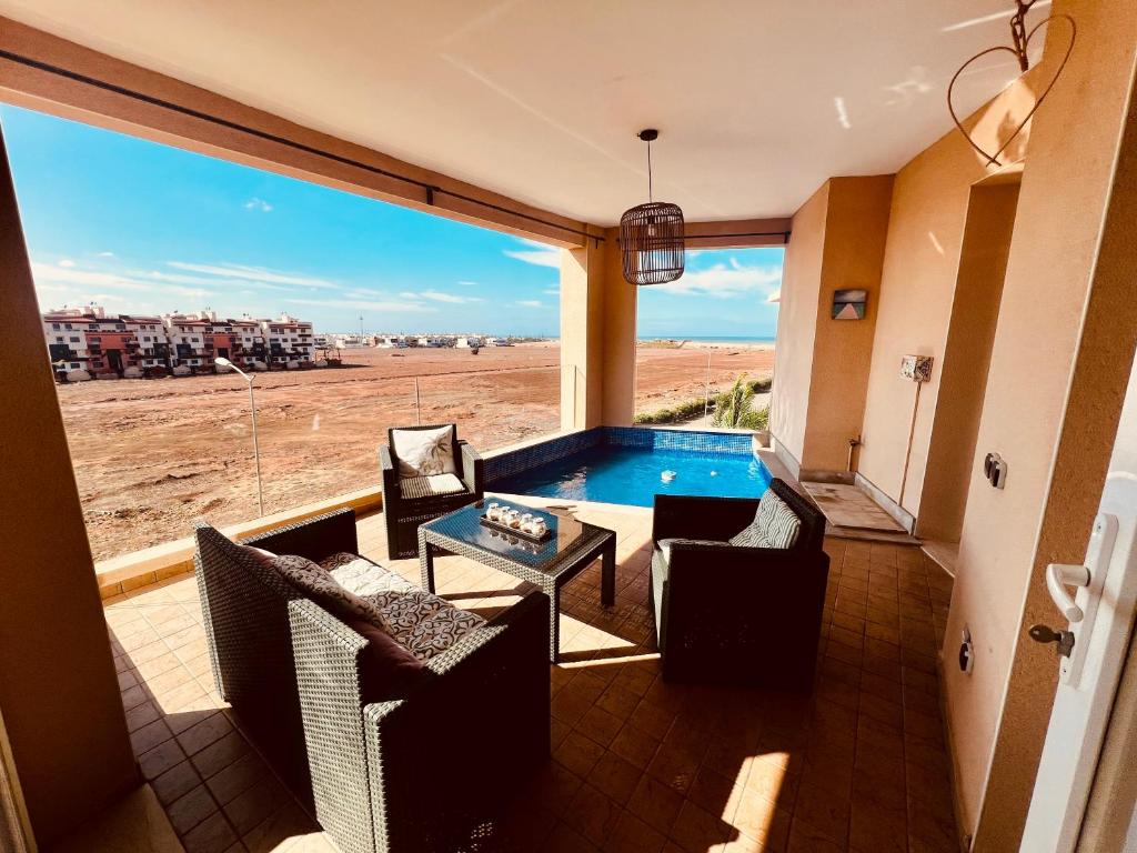 a balcony with a table and chairs and a swimming pool at Ocean Gem - Exclusive 2BR, Balcony Pool, Beach, Surf & Views in Bouznika