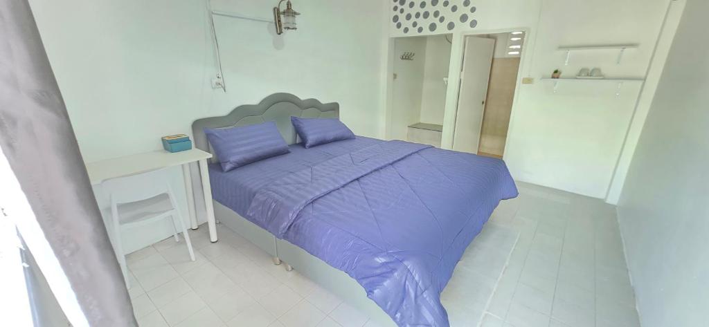 Bett mit lila Kissen in einem weißen Zimmer in der Unterkunft Khao Ban Eing in Ban Khlong Sai