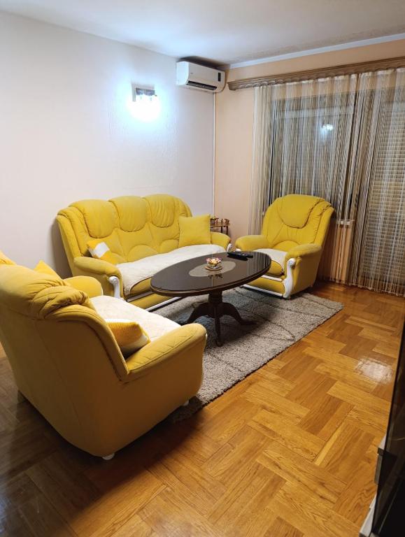 a living room with two yellow chairs and a table at Stan na dan Ilicka in Brčko