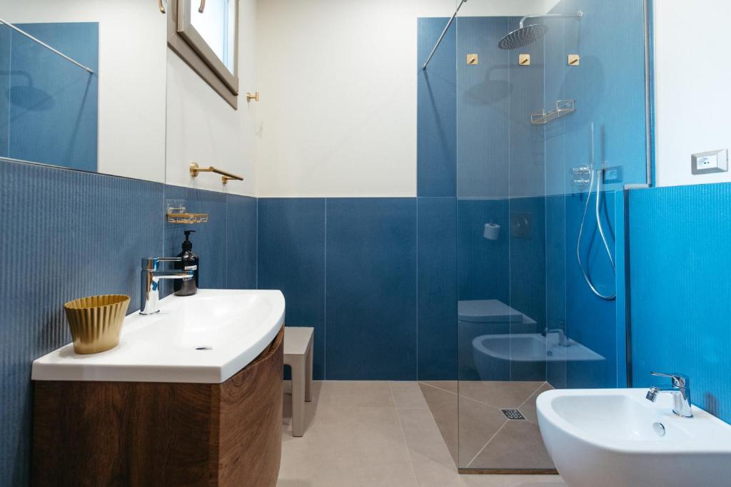 Un baño con paredes azules y un lavabo y una ducha. en Frontemare Appartamenti e Camere ELISABETTA, en Cesenatico