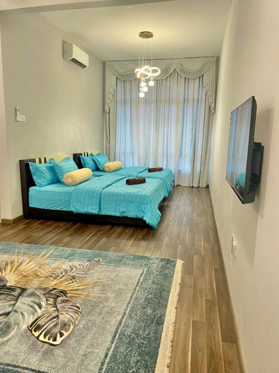 a bedroom with a blue bed and a flat screen tv at Amyra Suite Kuantan in Kuantan