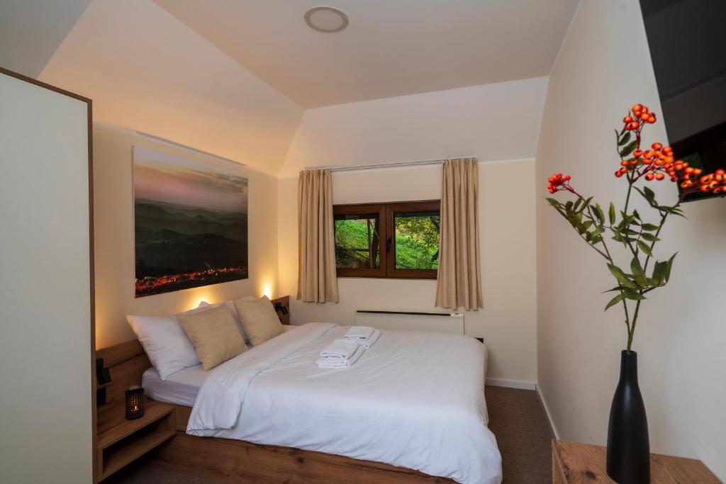 a bedroom with a white bed and a vase with flowers at Lisine Lepo Mesto Guesthouse & Spa in Strmosten