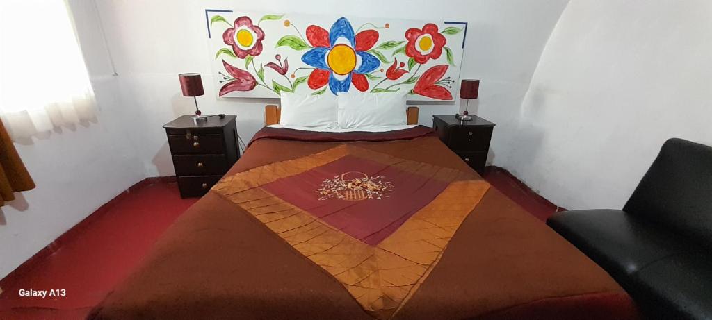 a bedroom with a bed with a painting on the wall at Kurumi Hostel in Cusco