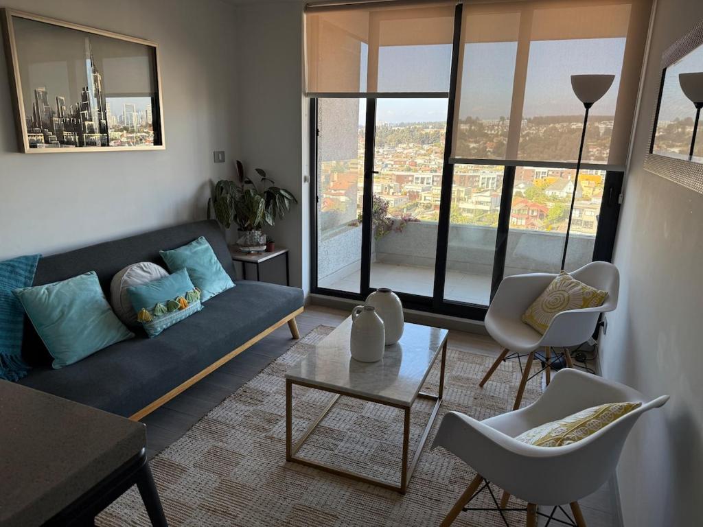 ein Wohnzimmer mit einem blauen Sofa und einem Tisch in der Unterkunft Departamento con vista a las Dunas y playa in Concón