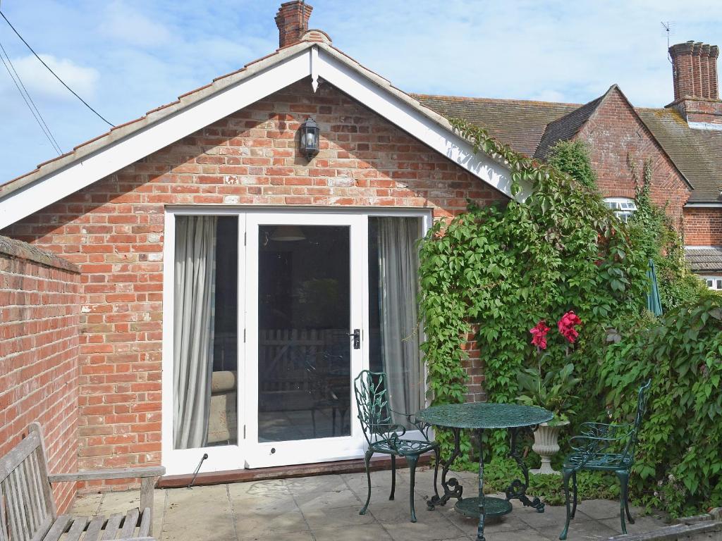 un patio con porta, tavolo e sedie di Bluebell Cottage ad Alburgh
