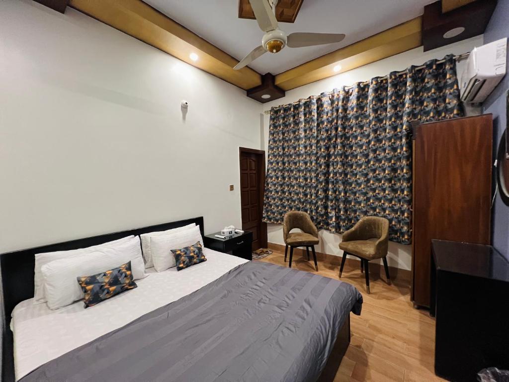 a bedroom with a bed and two chairs in it at Karachi Inn PECHS in Karachi