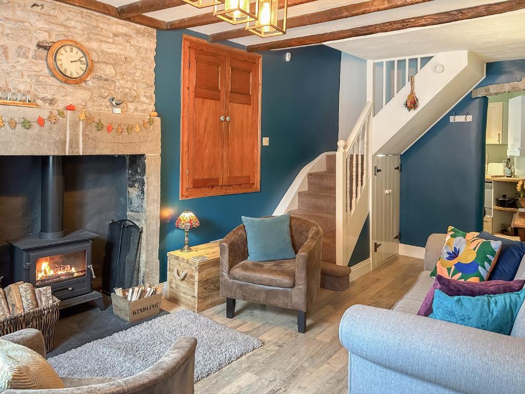 a living room with a fireplace and a staircase at Parsley Cottage in Tideswell