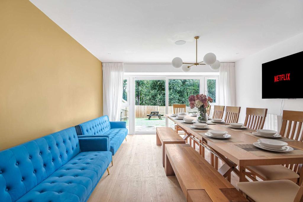 une salle à manger avec un canapé bleu et une table dans l'établissement The Roost Group - 5 Bed House Hot Tub & Pool Table, à St. Leonards