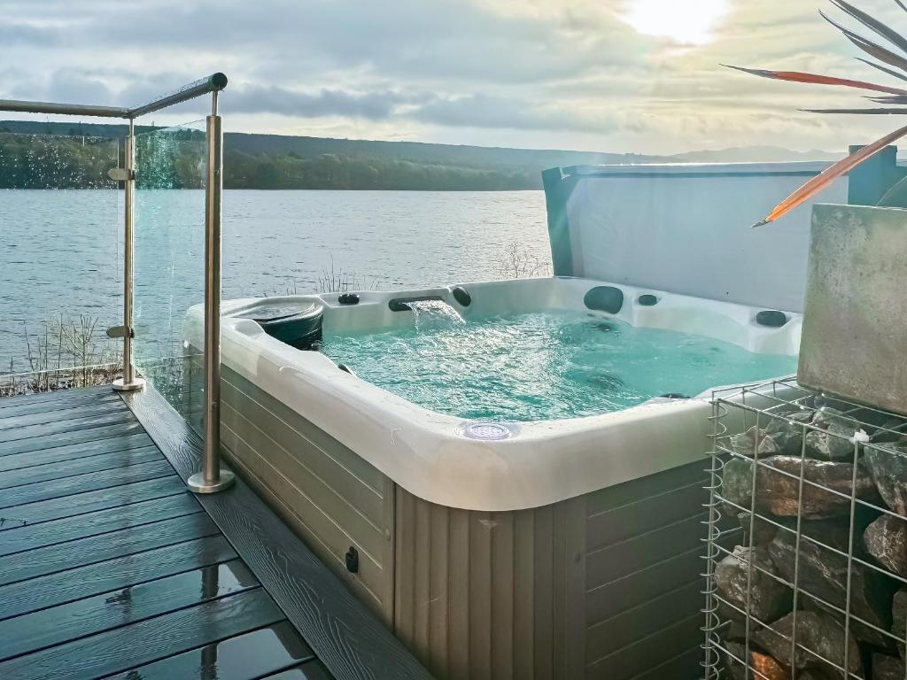 a jacuzzi tub sitting on a deck next to a lake at Kimcraigan Lodge in Lochend