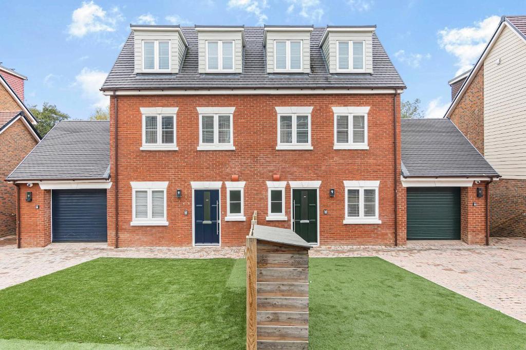 une grande maison en briques avec une pelouse devant elle dans l'établissement The Roost Group - 27 Guests Two Homes Hot Tub, à St. Leonards