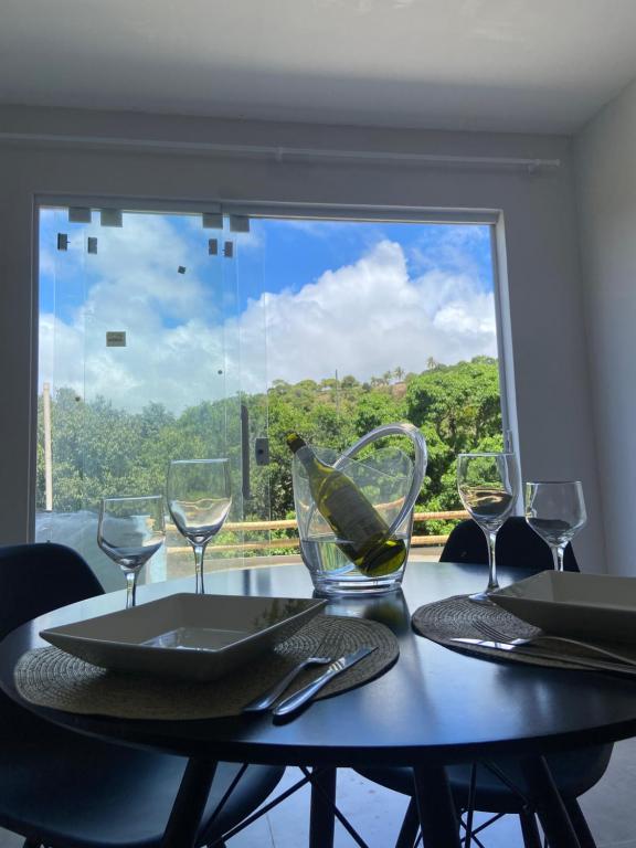 サン・ミゲル・ドス・ミラーグレスにあるCasa 2 quartos com área verde AnaManô Suitesのダイニングテーブル(ワイングラス付)、窓