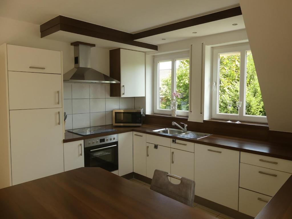 a kitchen with white cabinets and a sink and two windows at Monteurwohnung in ruhiger Lage in Spechtholzhock