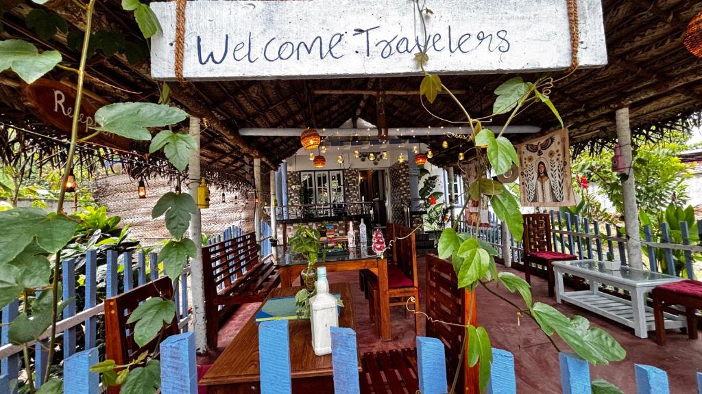 un restaurant avec une table et des chaises et un panneau indiquant les voyageurs d'accueil dans l'établissement Hideaway villa, à Varkala