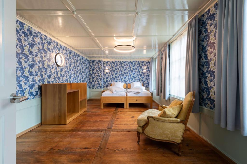 una camera da letto con carta da parati blu, un letto e una sedia di Krone Huttwil - Hotel Restaurant a Huttwil