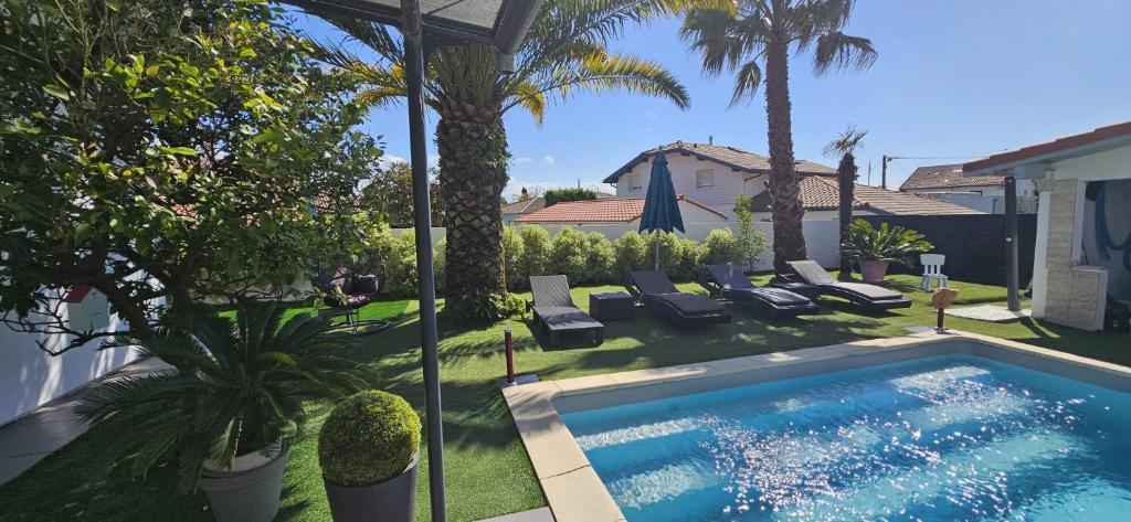 einen Hinterhof mit einem Pool und Palmen in der Unterkunft Villa familiale bayonne in Boucau