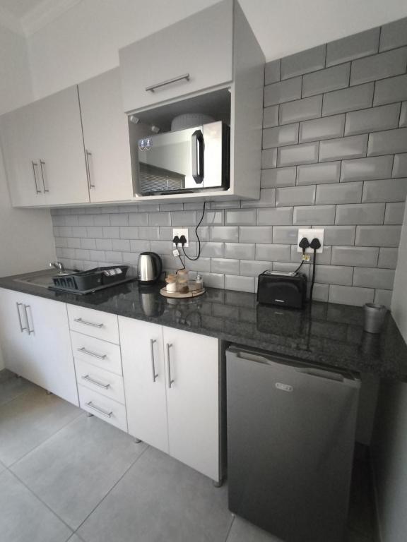 Una cocina con gabinetes blancos y una encimera negra. en Atloch, en Kimberley