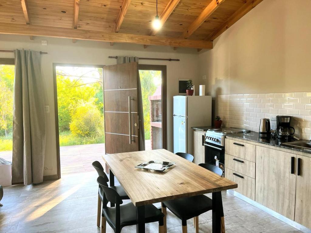 a kitchen with a wooden table and a table and chairs at Village De Las Sierras in Sierra de la Ventana