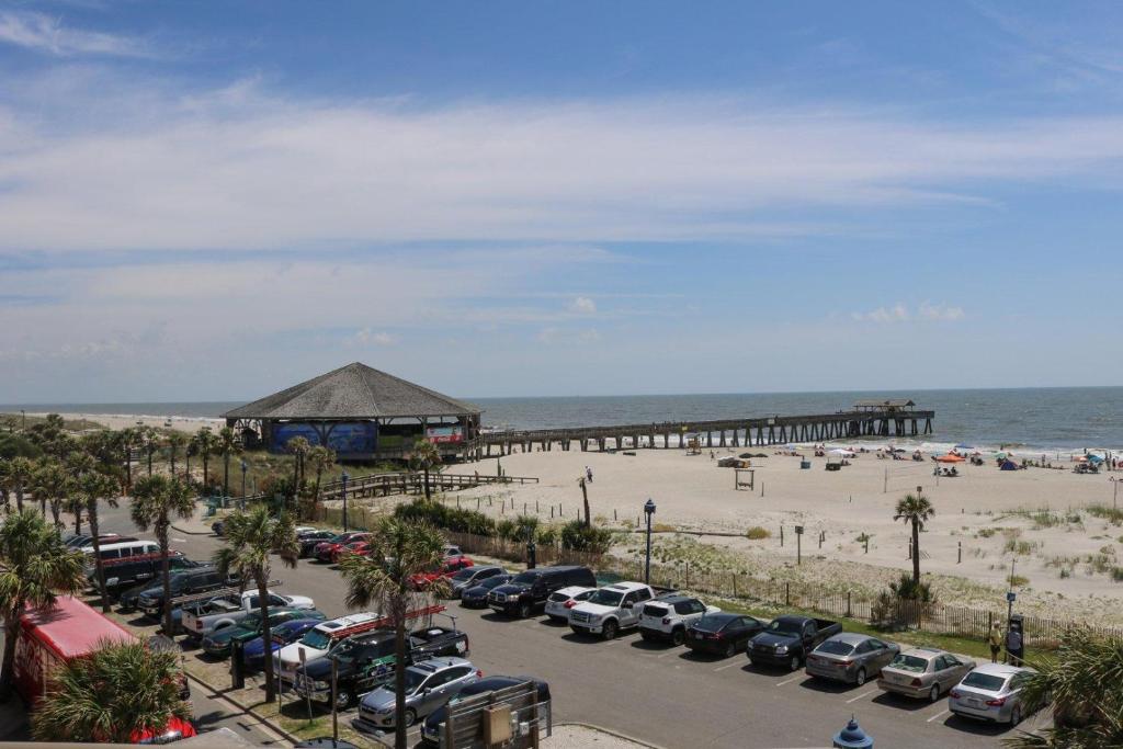 a parking lot next to a beach with a pier at Sandpiper 304 in Tybee Island