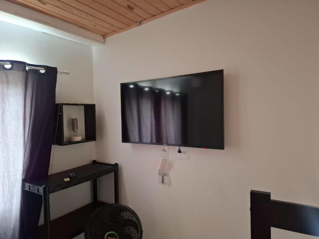 a flat screen tv on the wall of a room at Kitnet dos netos in Ubatuba