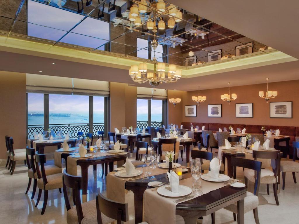 a dining room with tables and chairs and windows at CVK Park Bosphorus Hotel Istanbul in Istanbul