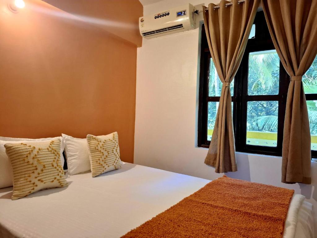 une chambre avec un lit avec des oreillers et une fenêtre dans l'établissement Agonda by Casa de Palmora, à Palolem