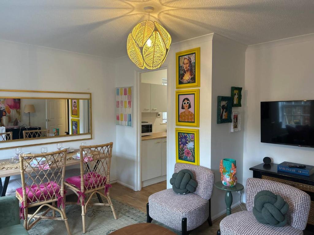 ein Wohnzimmer mit Stühlen und einem Tisch und einem Fernseher in der Unterkunft Stylish One Bedroom Apartment in Central Potton in Potton