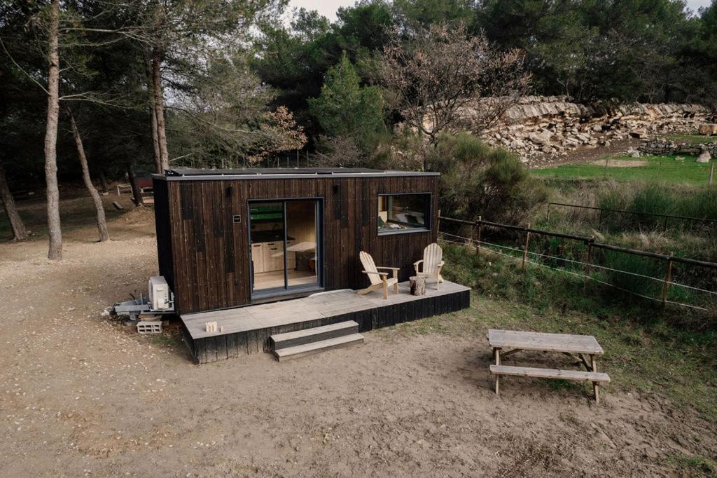 a small wooden cabin with a bench and a table at Parcel Tiny House Regagnas- au pied de la Sainte Victoire in Trets