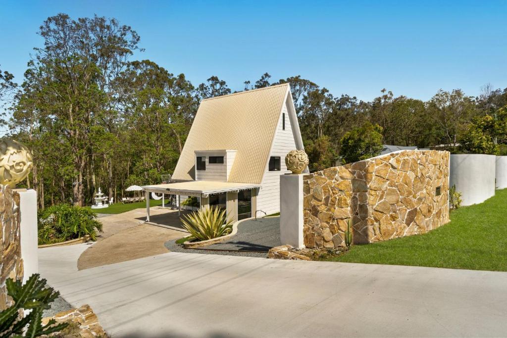 a house with a stone wall and a fence at Tranquil Hideaway in Mudgeeraba - Fully Fenced in Gold Coast