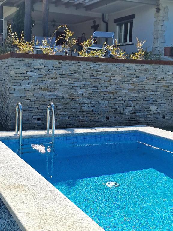 a swimming pool with blue water in front of a brick wall at I CARCIONI Infinity Pool in Belgirate