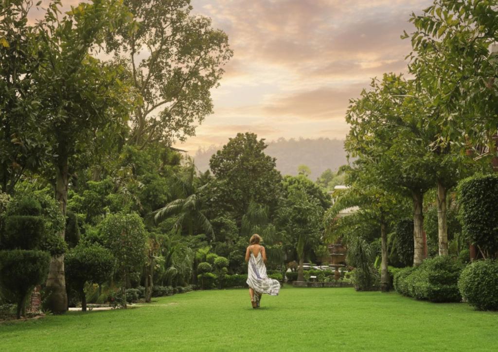 a woman walking through a park at Narayana Sanctuary Resort by SALVUS in Rishīkesh