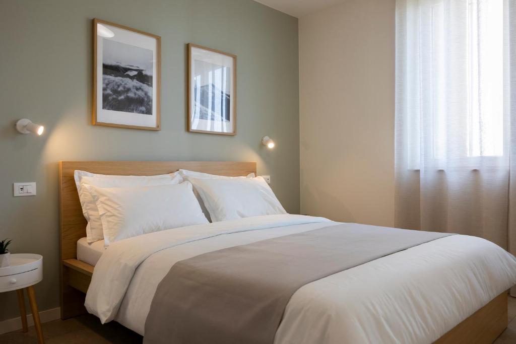 a bedroom with a bed with white sheets and a window at Casa Vistalago Mountain Lake Iseo Hospitality in Bossico