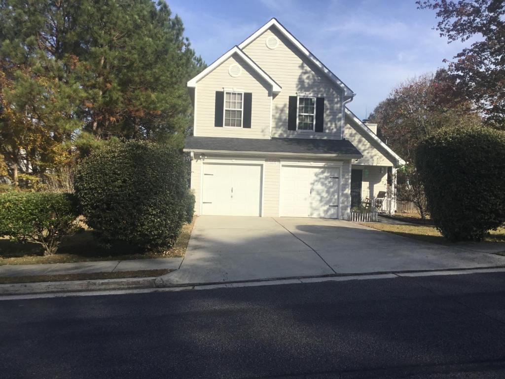 a white house with a garage on a street at Captivating Home near Downtown ATL in Conley