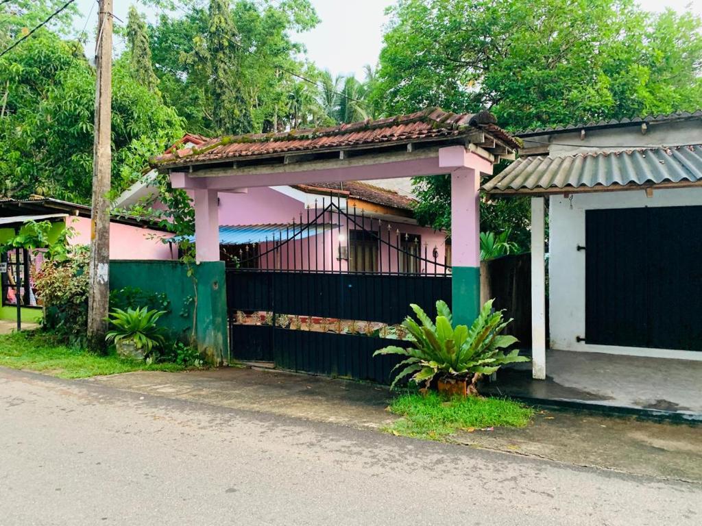 ein Haus mit einem grünen Zaun und einem Tor in der Unterkunft Sewwandi Home in Nikawatawana