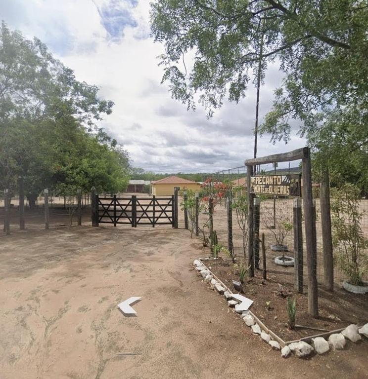 a fence with a sign in a dirt field at Recanto Monte das Oliveiras Hotel e Pousada in Tupim