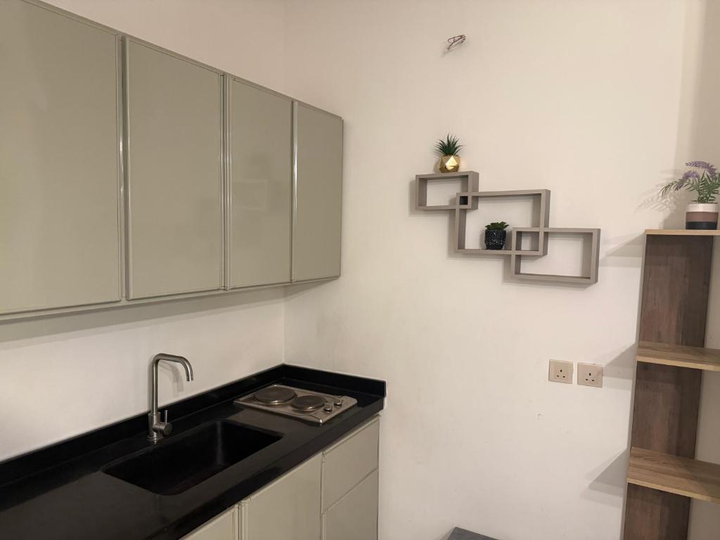 Una cocina con gabinetes blancos y un fregadero. en شاليهات سمو بارك 1, en Taif