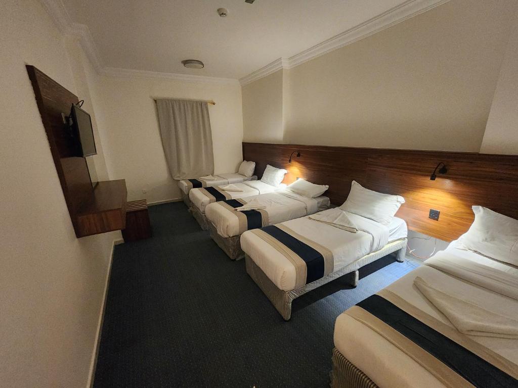 um quarto de hotel com quatro camas e uma televisão em اصول الجوهرة العزيزية Asoul Al Jawhara Al Azizia em Al ‘Azīzīyah