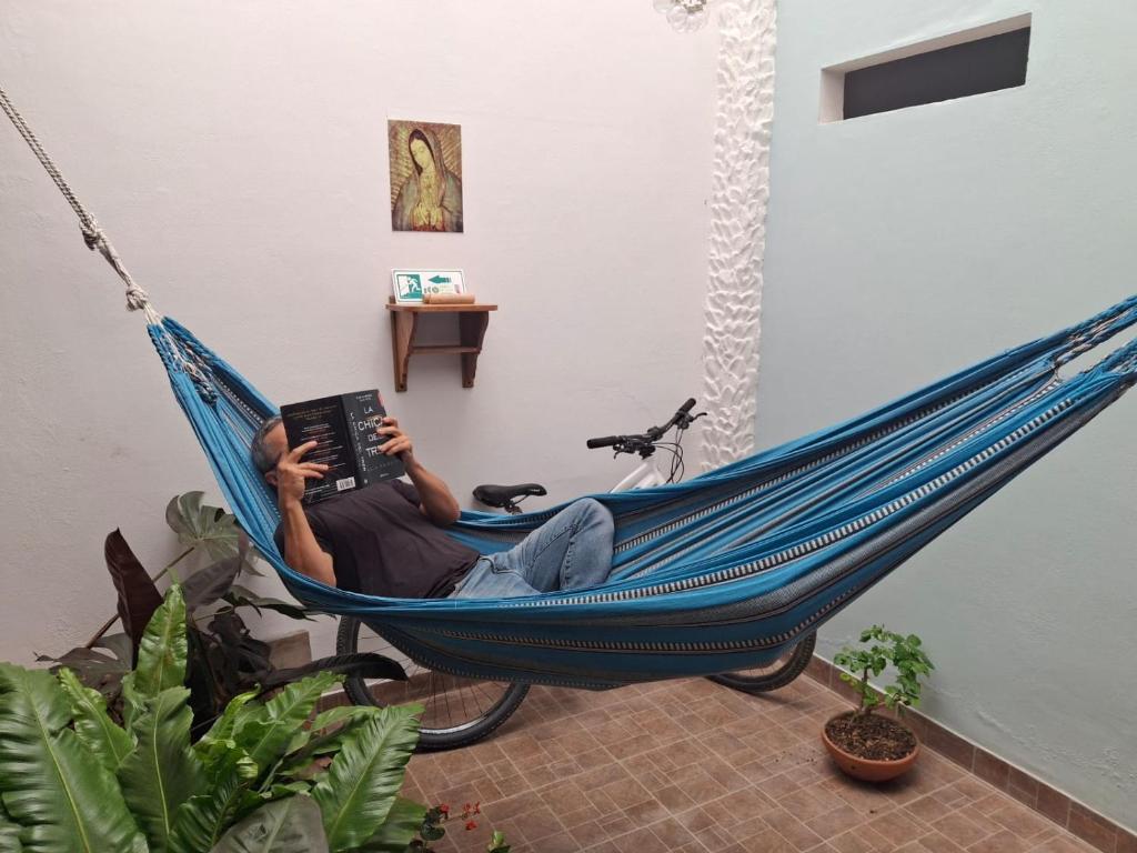 a man laying in a hammock reading a book at Hostal Naty luna - sede alterna in Jardin
