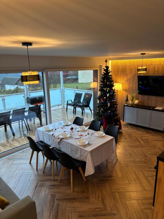ein Esszimmer mit einem Tisch und einem Weihnachtsbaum in der Unterkunft Domy na Roztoczu Aleja Lipowa B,G,J,K Sauna Jacuzzi Kajaki in Zwierzyniec