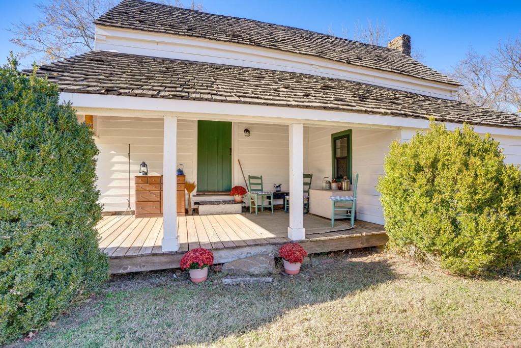 a white house with a wooden porch with plants at Blue Ridge Retreat! Cottage on the Rapidan River in Locust Dale