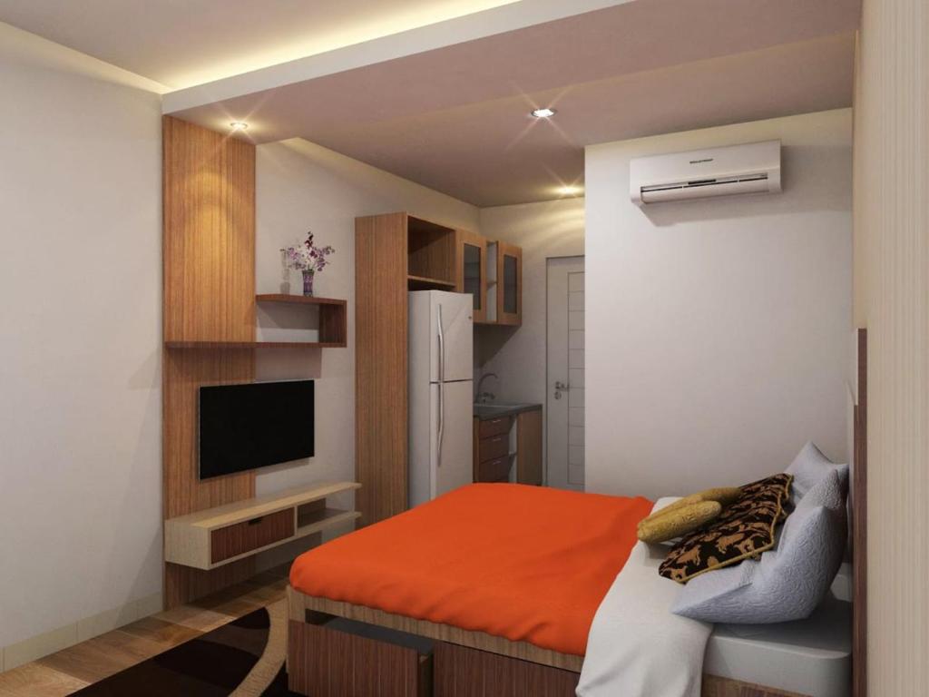 ein kleines Schlafzimmer mit einem orangefarbenen Bett und einem Kühlschrank in der Unterkunft Dina Cozy House in Jakarta
