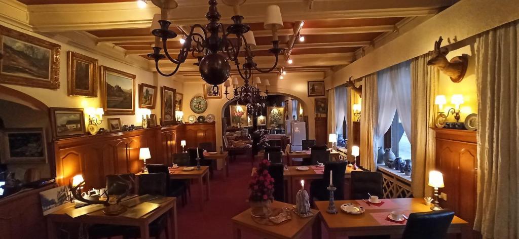 ラ・ロシュ・アン・アルデンヌにあるHotel Le Chaletのテーブルと椅子とシャンデリアのあるレストラン