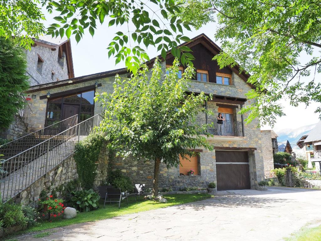 una casa de piedra con un árbol delante en Apartamentos Fogaron, en Saravillo