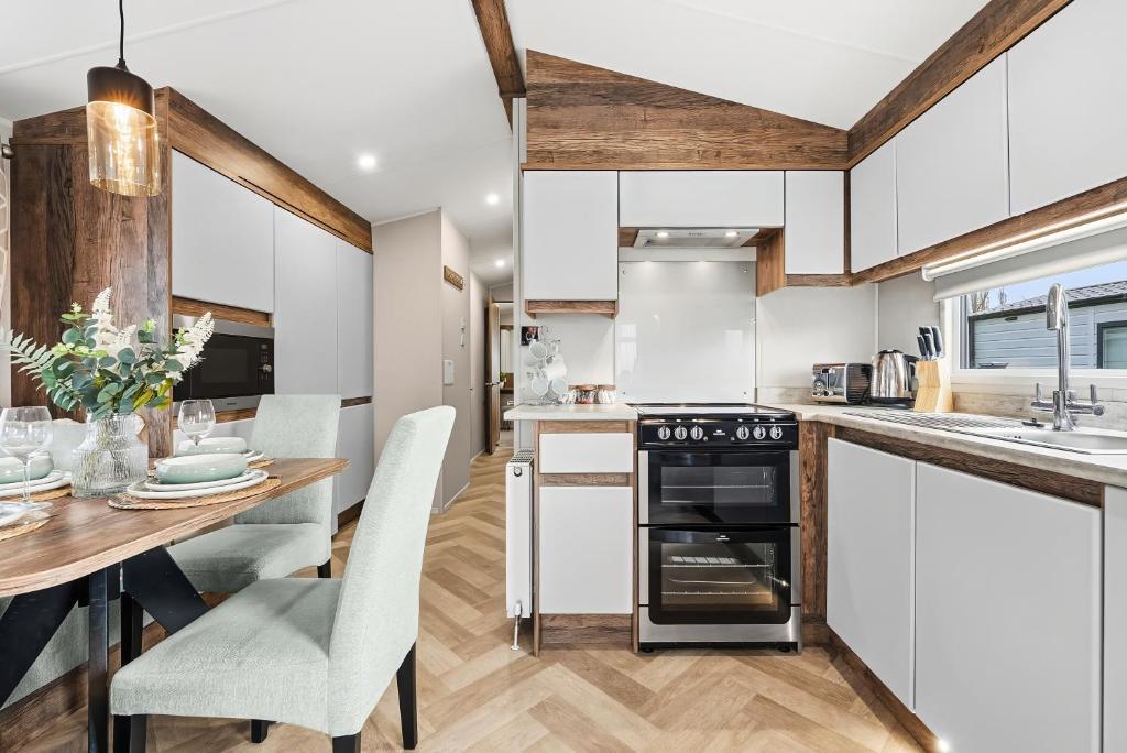 a kitchen and dining room with a table and chairs at Harbour Retreat at Cormorant View - Luxury Lodge with Hot Tub - Hayling Island - Mill Rythe Holiday Village in North Hayling
