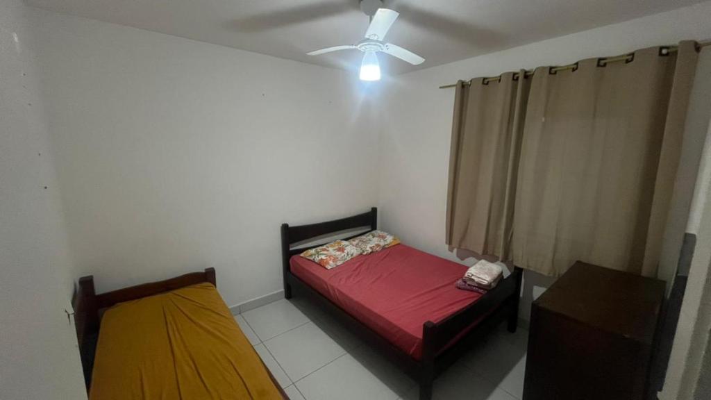 a small bedroom with a bed and a ceiling fan at Apartamento em Pitangueiras in Guarujá