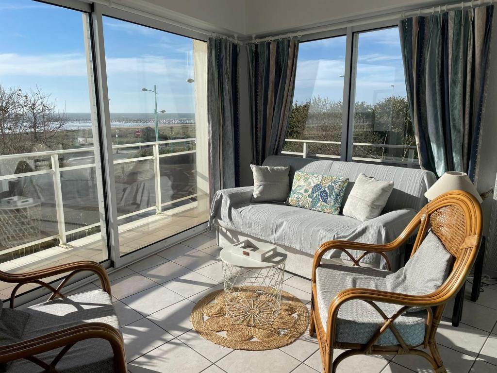 a living room with a couch and some windows at Appartement T2 vue mer les pieds dans l'eau avec parking privé in Saint-Jean-de-Monts
