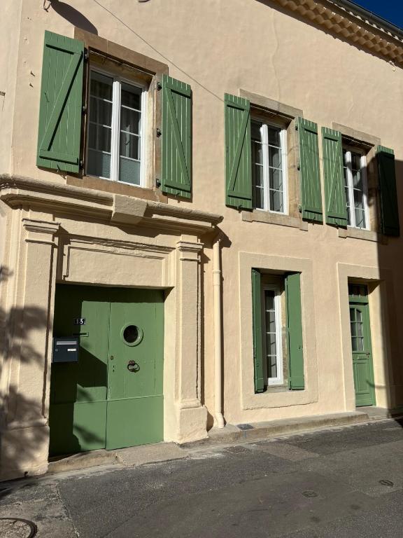 a building with a green door and windows at Studio - Cœur de Ville in Sérignan
