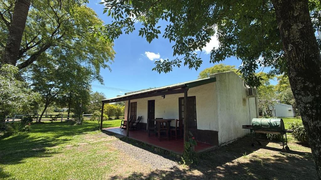 a small white building with a table in a yard at EL PASO IBERA, cabañas equipadasy piscina in Colonia Carlos Pellegrini
