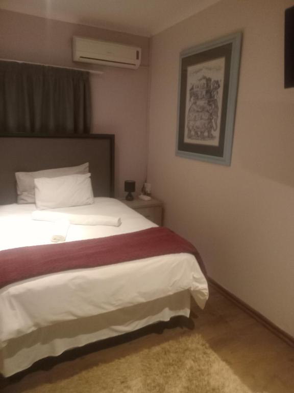 ein Schlafzimmer mit einem Bett mit einer rot-weißen Decke in der Unterkunft Good Times Cafe in Teyateyaneng