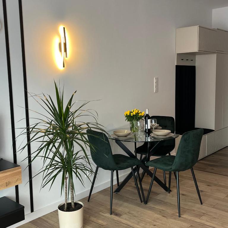 a dining room with a black table and green chairs at Apartamenty Dwie Rzeki in Łódź