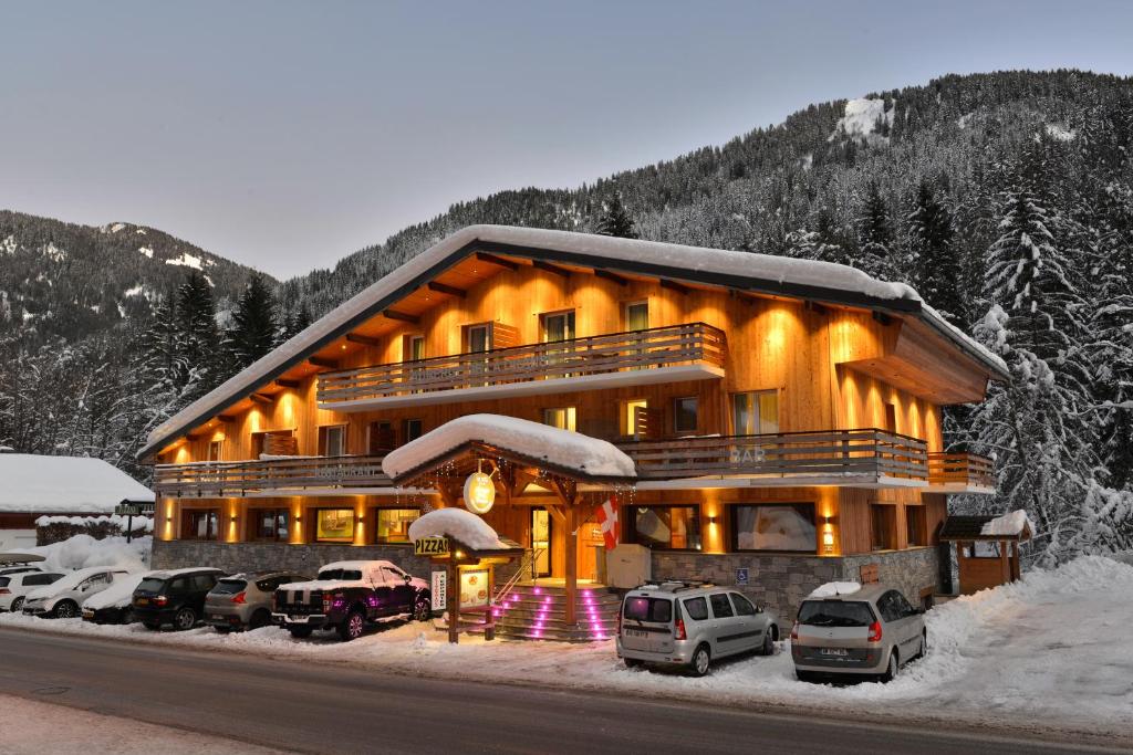 a large building with cars parked in front of it at Auberge de la Dranse in Châtel